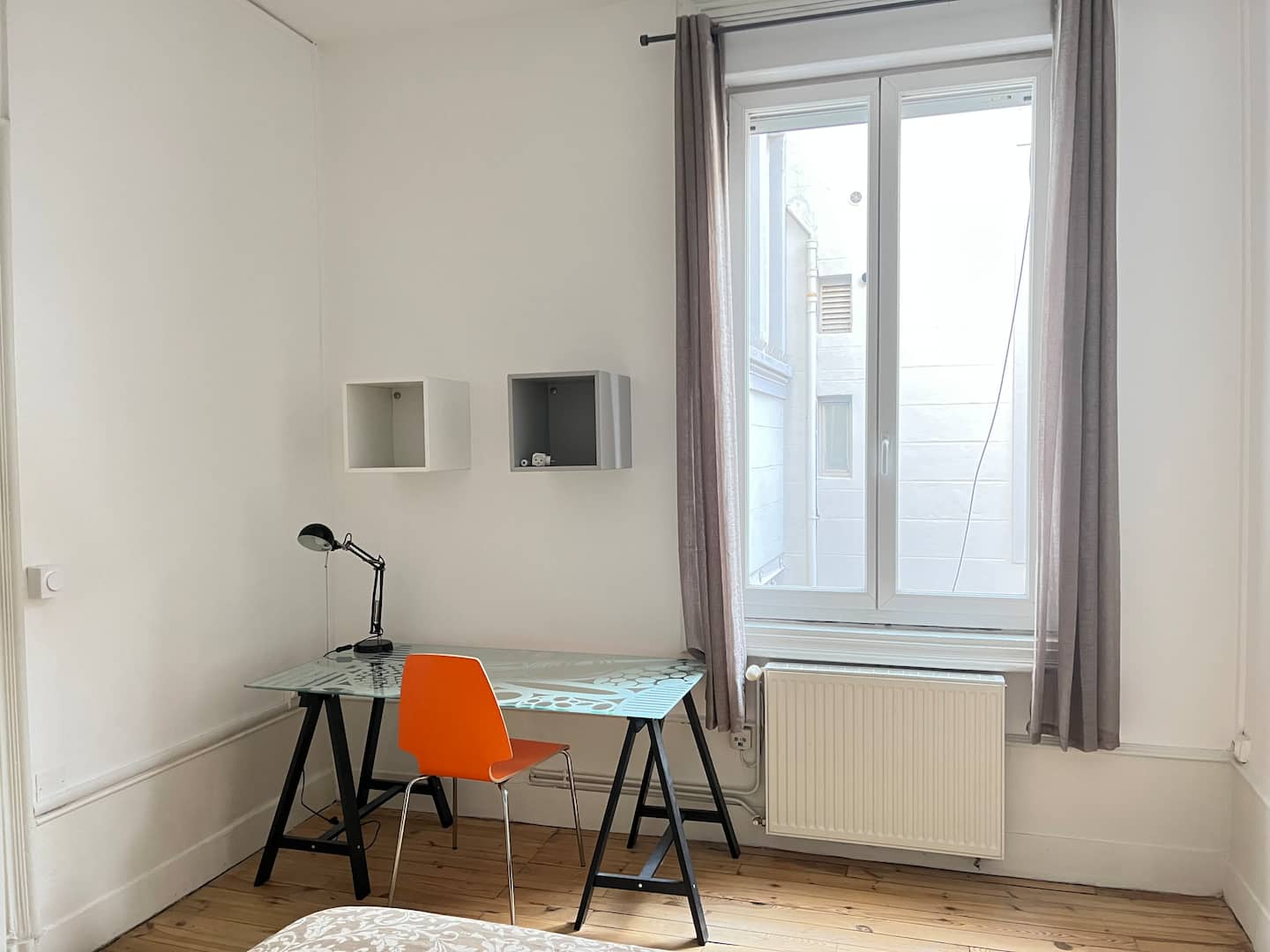 Espace bureau d’une chambre avec plateau à motifs, chaise orange et grande fenêtre